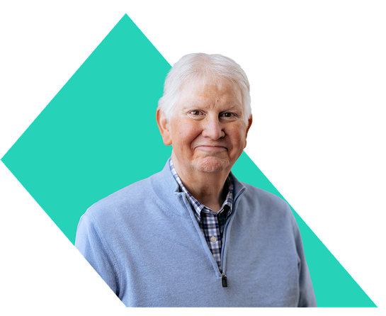 PYLARIFY Patient Bryan Bryan, a PYLARIFY patient, smiling in a collared button-up shirt and sweater