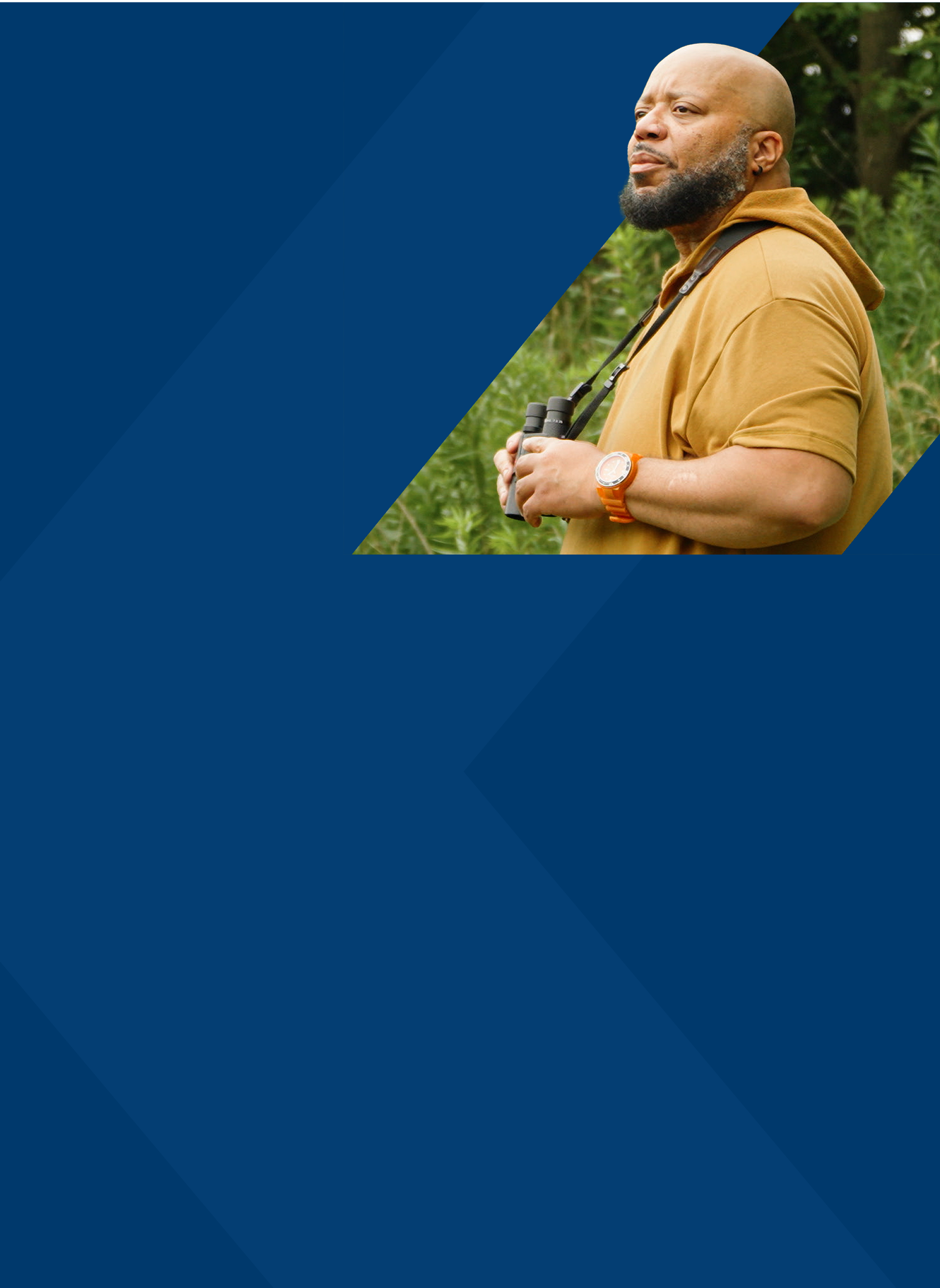 PYLARIFY Patient Al Binoculars Al, a PYLARIFY patient, standing outside in nature, holding binoculars